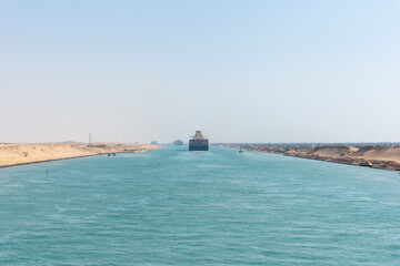 Fototapeta premium Suez Canal, panorama view of the canal with blue water and transiting ship on the horizon. 