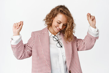 Dancing business woman smiling, raising hands free in air, having fun and relaxing, standing in...