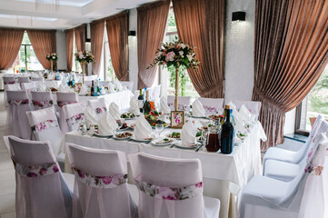 A composition of flowers and green is on a festive table at the wedding banquet hall. Stands, sign number. Close up.