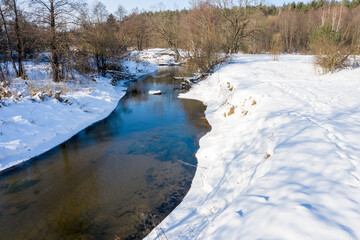 Drone shot flying on forest and river in winter.