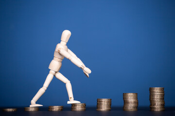 Stacks of golden coins like income graph and wooden man walking.