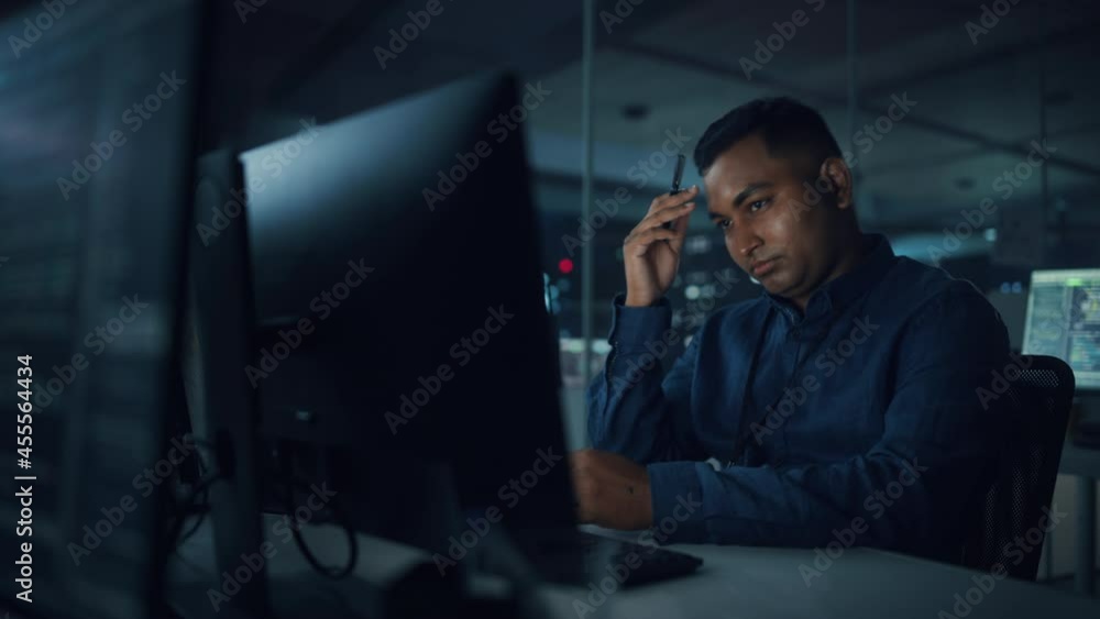 Poster Night Office: Portrait of Handsome Indian Man in Working on Desktop Computer. Digital Entrepreneur Typing, Creating Software, e-Commerce App Design, Programming. Thoughtful Man Seeking Solution