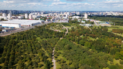 Obraz premium City landscape. Nearby there is a park area. Blue sky with white clouds. Aerial photography.