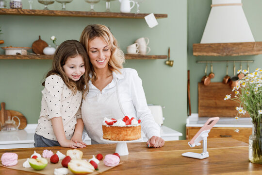 Happy Cool Chef Cook Baker Mom Woman In White Shirt Work Baby Girl Helper Use Mobile Cell Phone Do Selfie Shot At Kitchen Table Home Cooking Food Process Concept Mommy Little Kid Daughter Prepare Cake