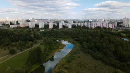 Fototapeta premium City landscape. Nearby there is a park area. Blue sky with white clouds. Aerial photography.