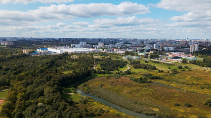 Fototapeta na wymiar City landscape. Nearby there is a park area. Blue sky with white clouds. Aerial photography.