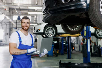 Young fun professional technician mechanic man wears denim blue overalls t-shirt use hold laptop pc...
