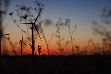 Fototapeta na wymiar Wind Turbines produce energy n motion silhouette at sunset