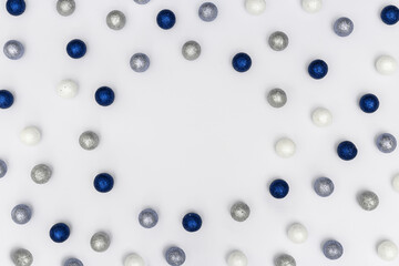 Bright winter holiday frame with sparkling silver and blue balls on white background with copy space.