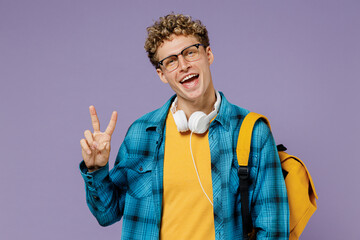 Young boy teen student in casual clothes backpack headphones glasses show victory v-sign gesture isolated on plain pastel violet background studio. Education in high school university college concept.