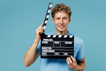 Smiling vivid cheerful young curly man 20s years old wears azure t-shirt looking camera holding...