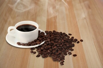 A cup of coffee among selected coffee beans scattered on a table,