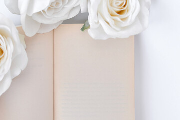 a book and white roses on the table, empty space for title