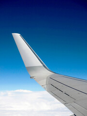 Curved wing tip of a passenger plane against a deep blue sky. Copy space. No people.