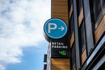 Low angle view of a baby blue digital parking sign for a parking garage in a shopping district downtown