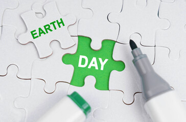 White puzzles lie on a green background, in place of an open puzzle it is written - earth day