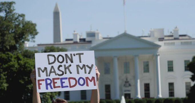 A man holds a DON'T MASK MY FREEDOM protest sign in front of the White House. Face mask mandates was a hot topic during the coronavirus pandemic.	