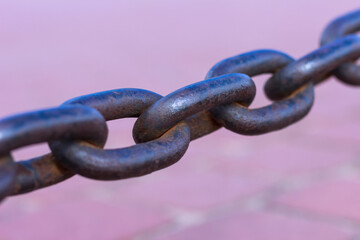 Heavy forged chain on the fence of the Neva embankment. The links of an old chain, illuminated by the sun, close-up.