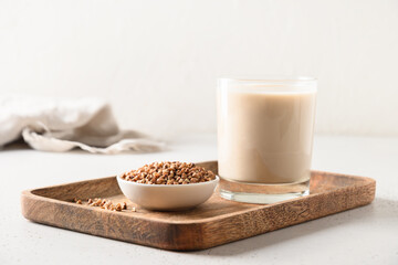 Lactose free healthy buckwheat milk served in drinking glass with grain ingredient on a white background. Horizontal orientation. Copy space.