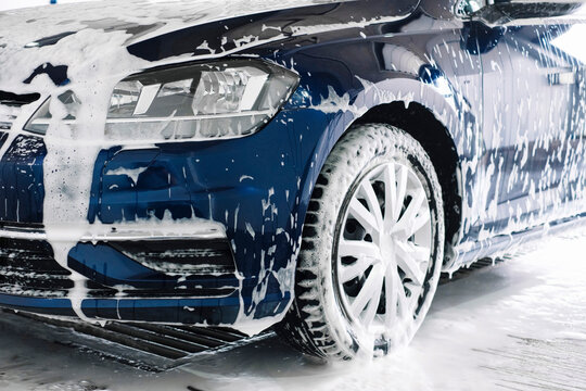 Manual car wash with white soap, foam on the body. Washing Car Using High Pressure Water.