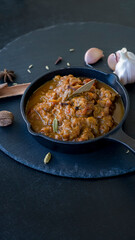 Traditional Indian beef curry served iron-cast. World cuisine. Black slate background.