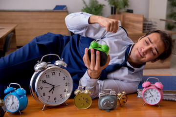 Young male employee sleeping in the office in time management co