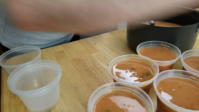 Home cooking - Transferring tomato soup into plastic containers to be stored in fridge or freezer later.