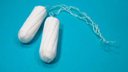 Two medical tampons on a blue background. Hygienic white tampon for women. Cotton swab. Menstruation, means of protection. 