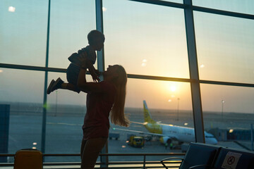 mother meet her son at the airport and pick him up in his arms.