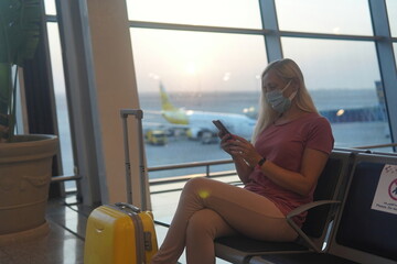 blonde woman sitting at the airport and waiting for the plane.