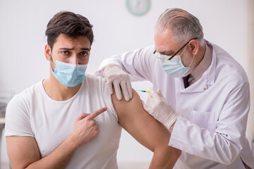 Young male patient visiting old male doctor in vaccination conce