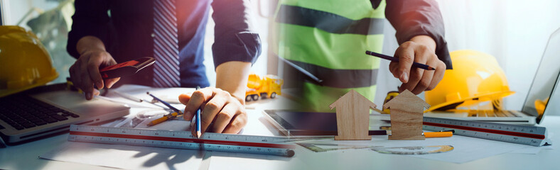 Two colleagues discussing data working and tablet, laptop with on on architectural project at construction site at desk in office