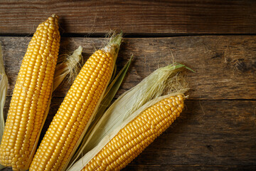 Fresh corn on the cob on a rustic wooden table, close up.