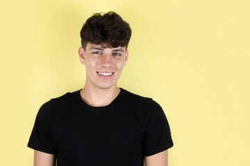 Portrait of a handsome teenage boy with a beautiful smile and white teeth on a yellow background....