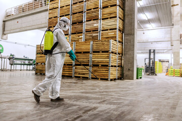 Person in a white protective suit refreshing and cleaning a public warehouse indoor space. Fight against COVID 19, coronavirus life, stay healthy, keep social distance, stop spreading corona virus