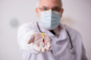 Old male doctor in vaccination concept