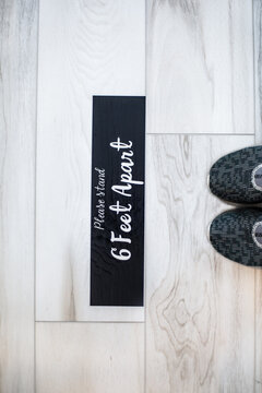 "Please stand 6 feet apart" on floor beside shoes