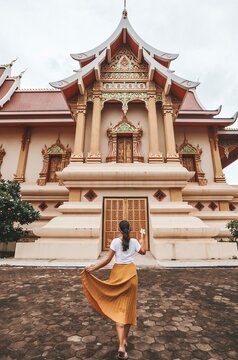 Back view of woman wearing long skirt standing in front of Pha That Luang Vientiane
