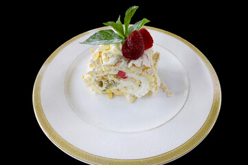 meringue roll with mascarpone cream and fresh strawberries in a white plate on a black background, decorated with fresh mint sprigs