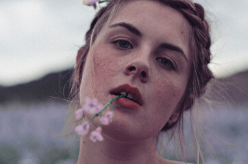 Close-up of woman with pink petaled flowers in her mouth