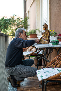 Elderly man cleaning a small Buddha Statue