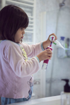 Girl putting toothpaste on toothbrush