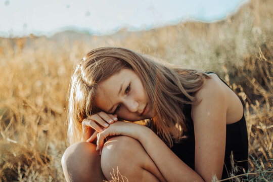 Girl Sitting On Yellow Grass Field