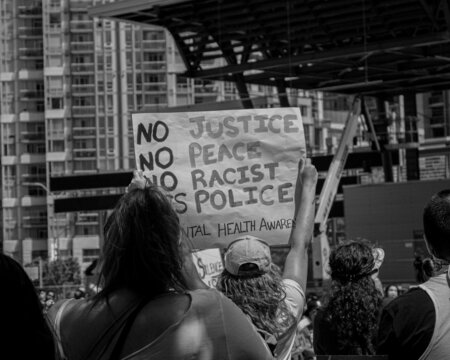 Grayscale photo of banner with words " No Justice No Peace No Racist " held at protest
