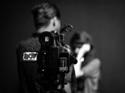 Grayscale photo of video recording man and woman
