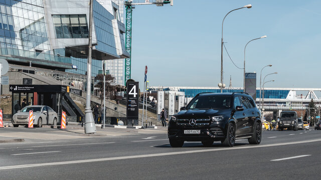 Black Mercedes-Benz GLS 450 4MATIC X167 on the city road. Premium SUV fast driving on road in the city with urban background
