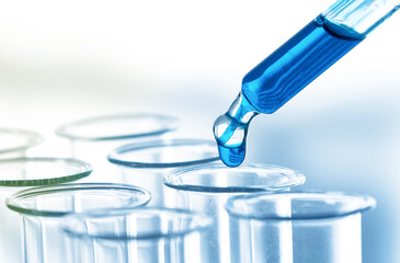 Pipette adding fluid to one of several test tubes .medical glassware