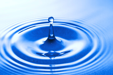 Falling water drop close up in blue.