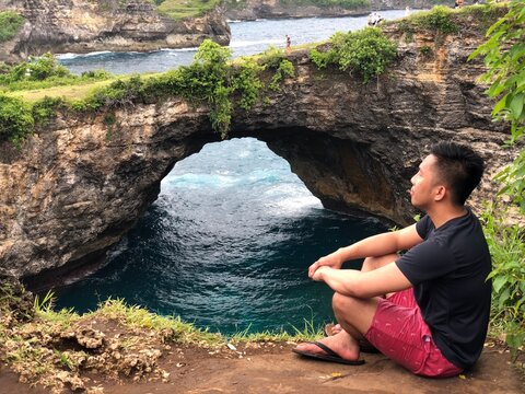 Man sitting on ground at Crystal Bay beach in Nusa Penida island  in Indonesia