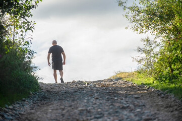 The man climbed up the hill into the light.